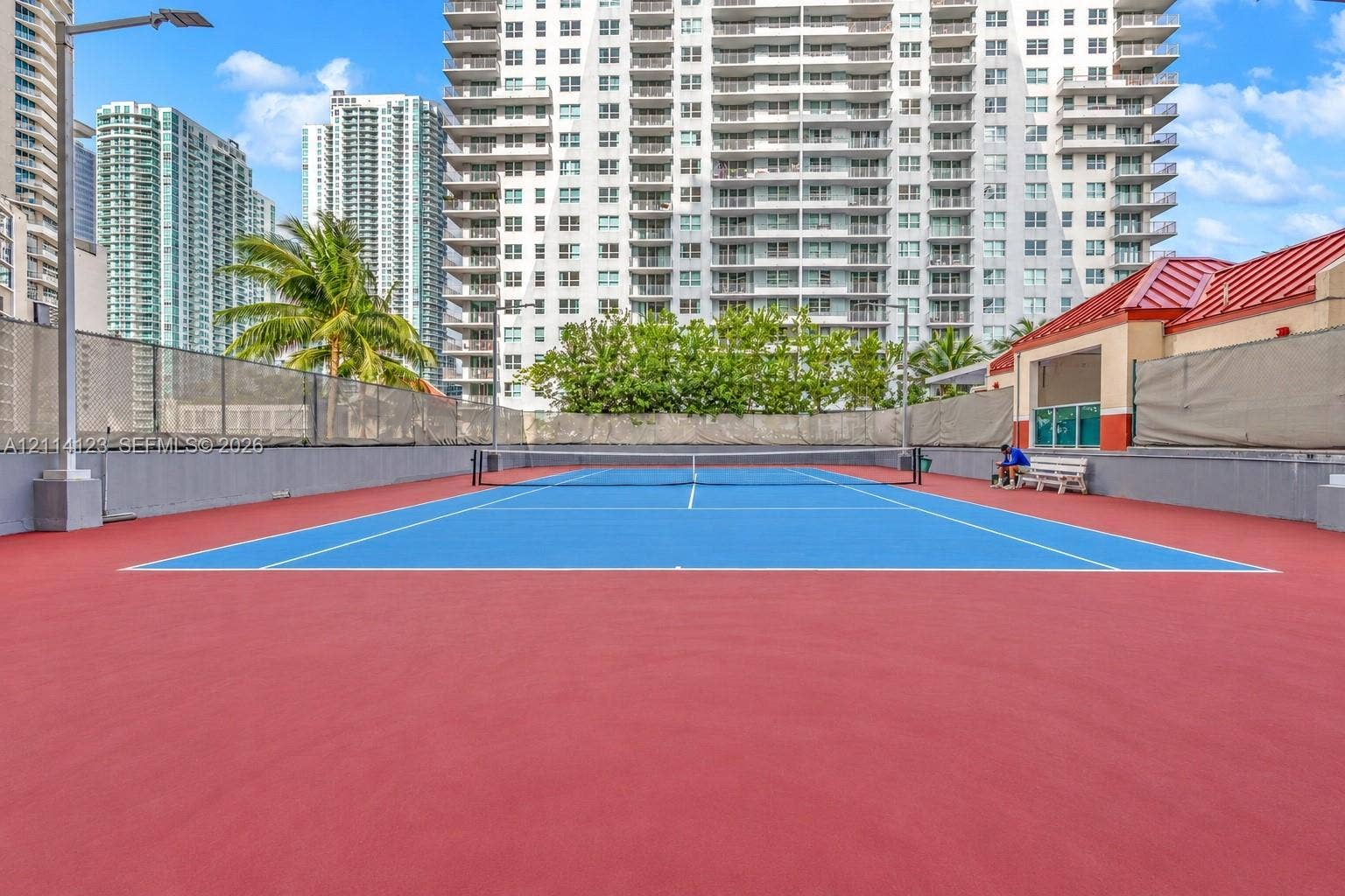 1155 Brickell Bay Drive, #2609, Miami, FL 33131 Tennis court featuring a high-contrast blue and red surface, perimeter fencing, and built-in lighting