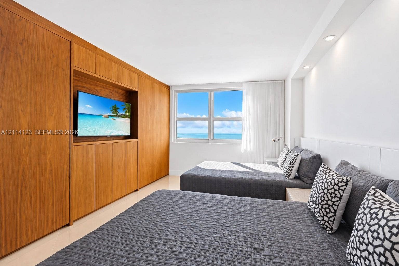 1155 Brickell Bay Drive, #2609, Miami, FL 33131 Custom wood-veneer cabinetry with integrated media shelving, large windows with water scenery, and recessed lighting