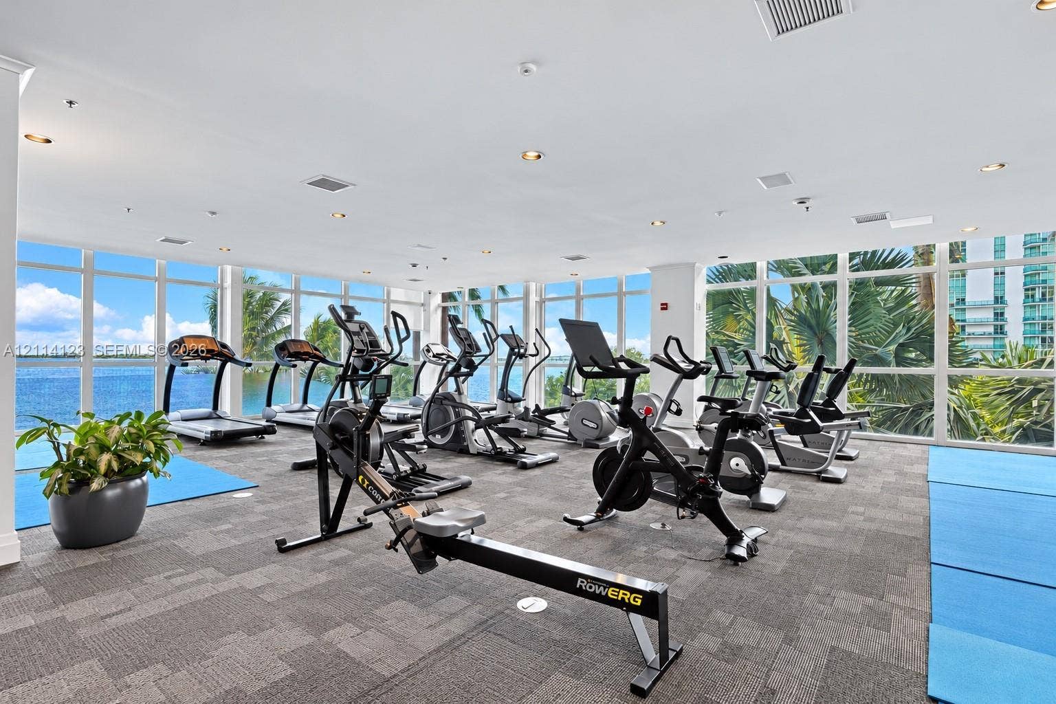 1155 Brickell Bay Drive, #2609, Miami, FL 33131 Fitness center featuring floor-to-ceiling windows, panoramic water exposure, recessed lighting, and carpeting