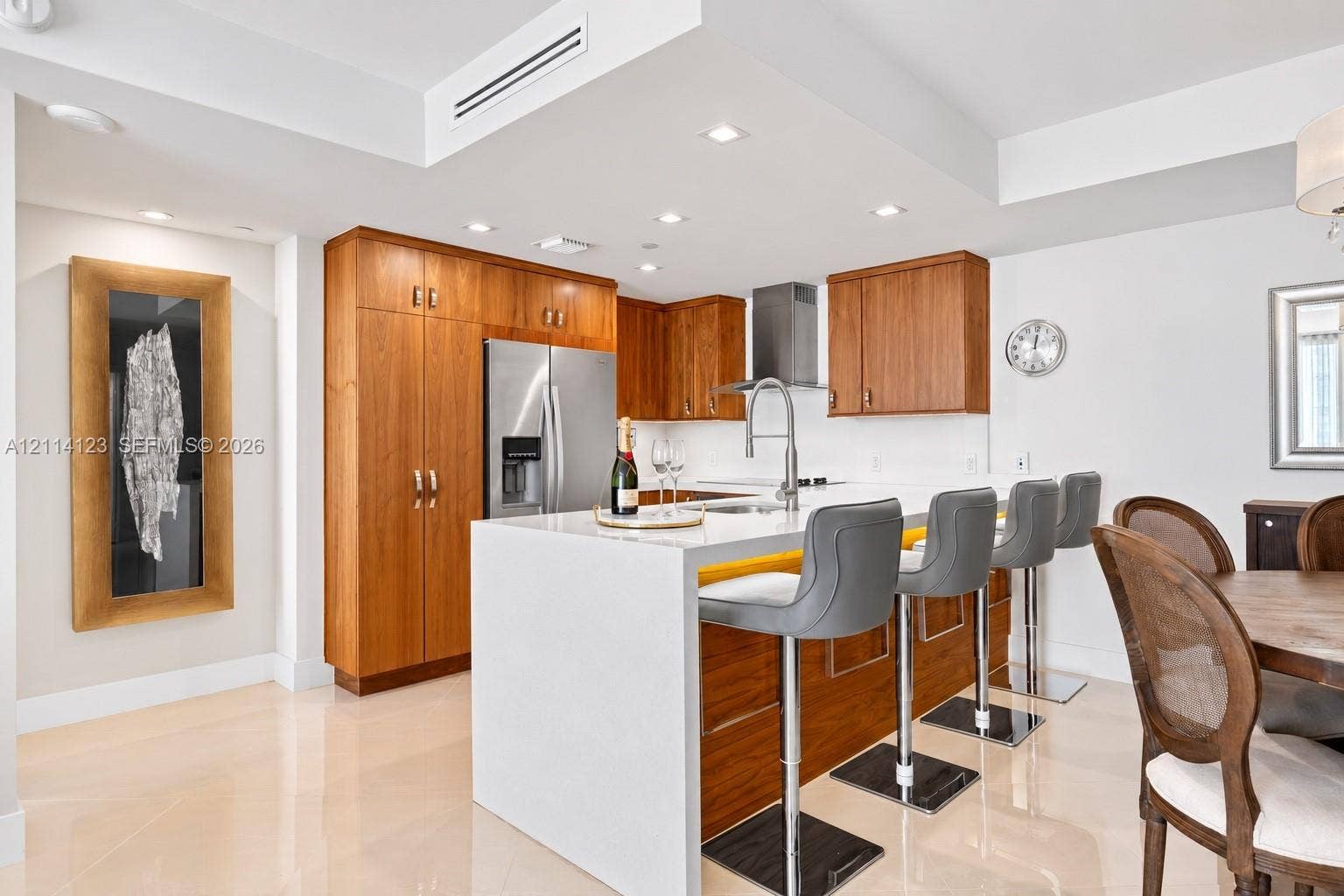 1155 Brickell Bay Drive, #2609, Miami, FL 33131 Kitchen featuring custom wood cabinetry, an expansive waterfall-edge island with stone-surface countertop, stainless steel appliances, recessed ceiling lighting, and polished stone flooring