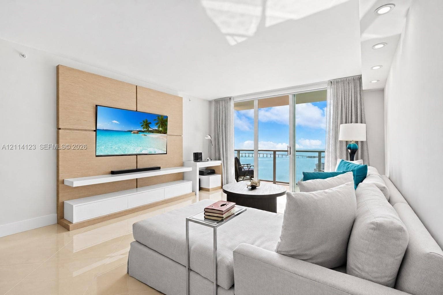 1155 Brickell Bay Drive, #2609, Miami, FL 33131 Living area featuring floor-to-ceiling glass sliding doors, custom wood-paneled accent wall with built-in cabinetry, polished stone flooring, and recessed ceiling lighting