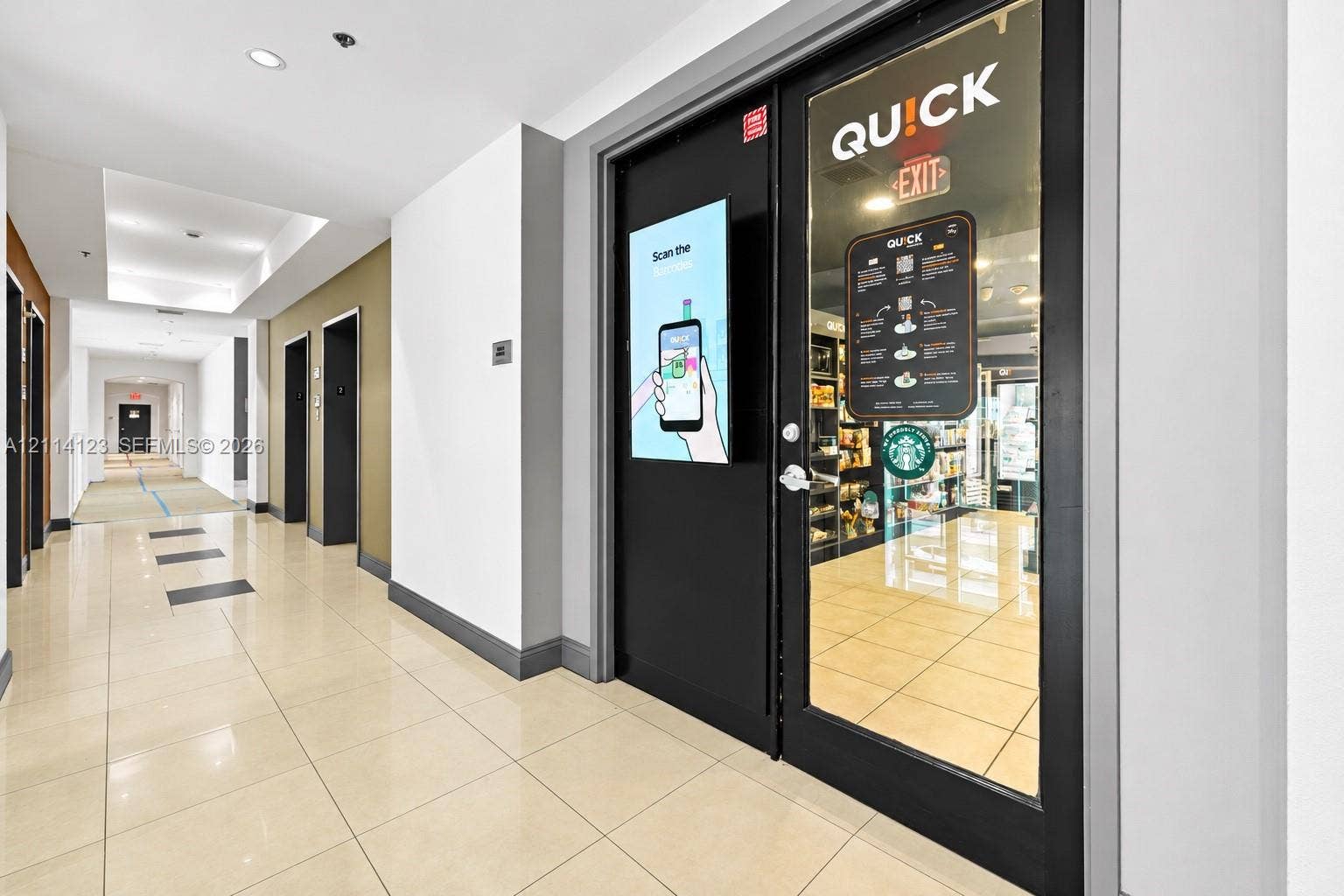 1155 Brickell Bay Drive, #2609, Miami, FL 33131 Common area hallway featuring polished tile flooring, recessed ceiling lighting, and a glass-paneled entry door with integrated digital signage