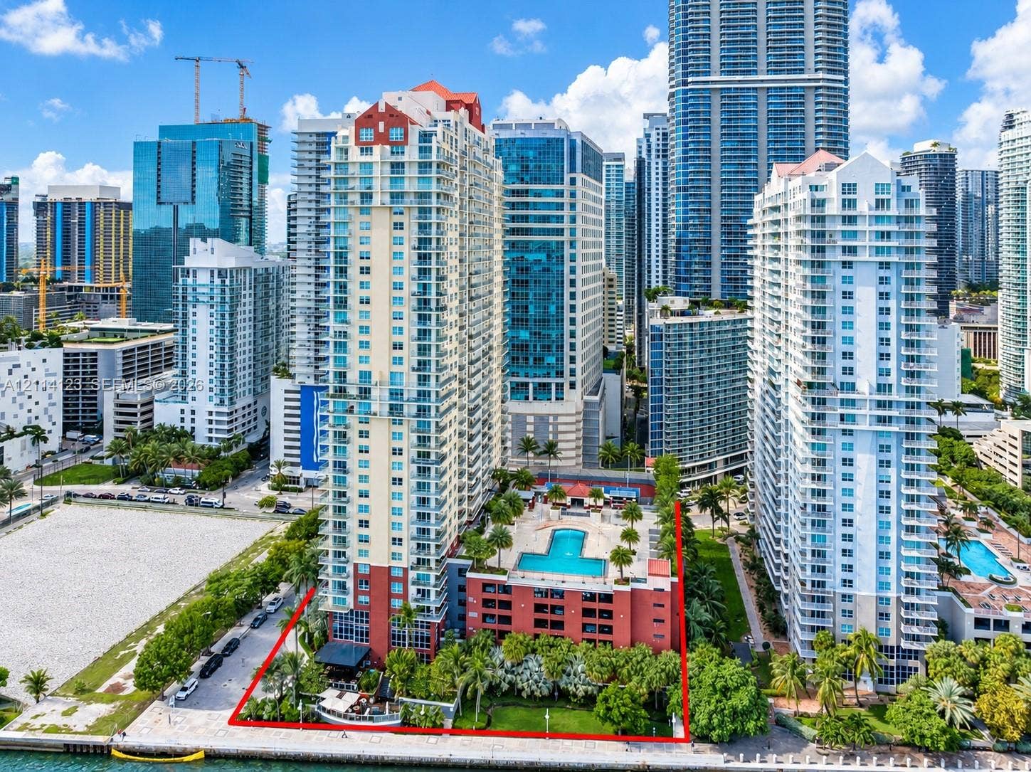 1155 Brickell Bay Drive, #2609, Miami, FL 33131 High-rise residential complex featuring an elevated pool deck, mature landscaping, ground-level waterfront promenade, and multi-story structural parking