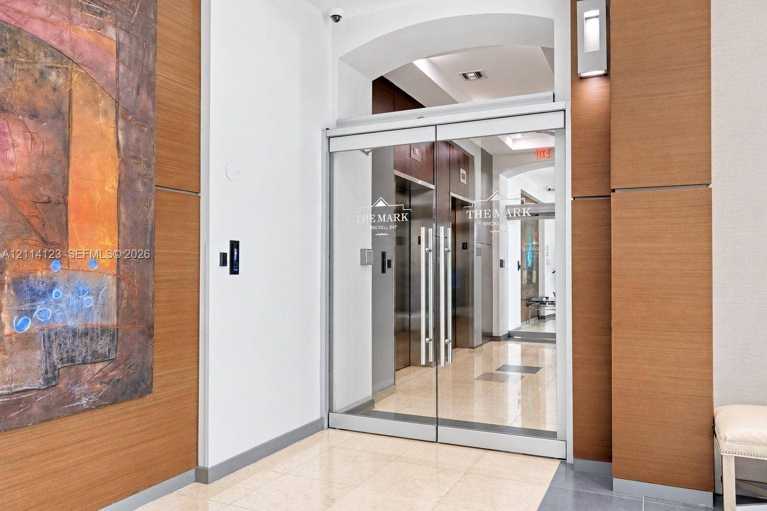 1155 Brickell Bay Drive, #2609, Miami, FL 33131 Entrance featuring glass double doors, polished stone flooring, wood-panel wall accents, and recessed wall-mounted sconces