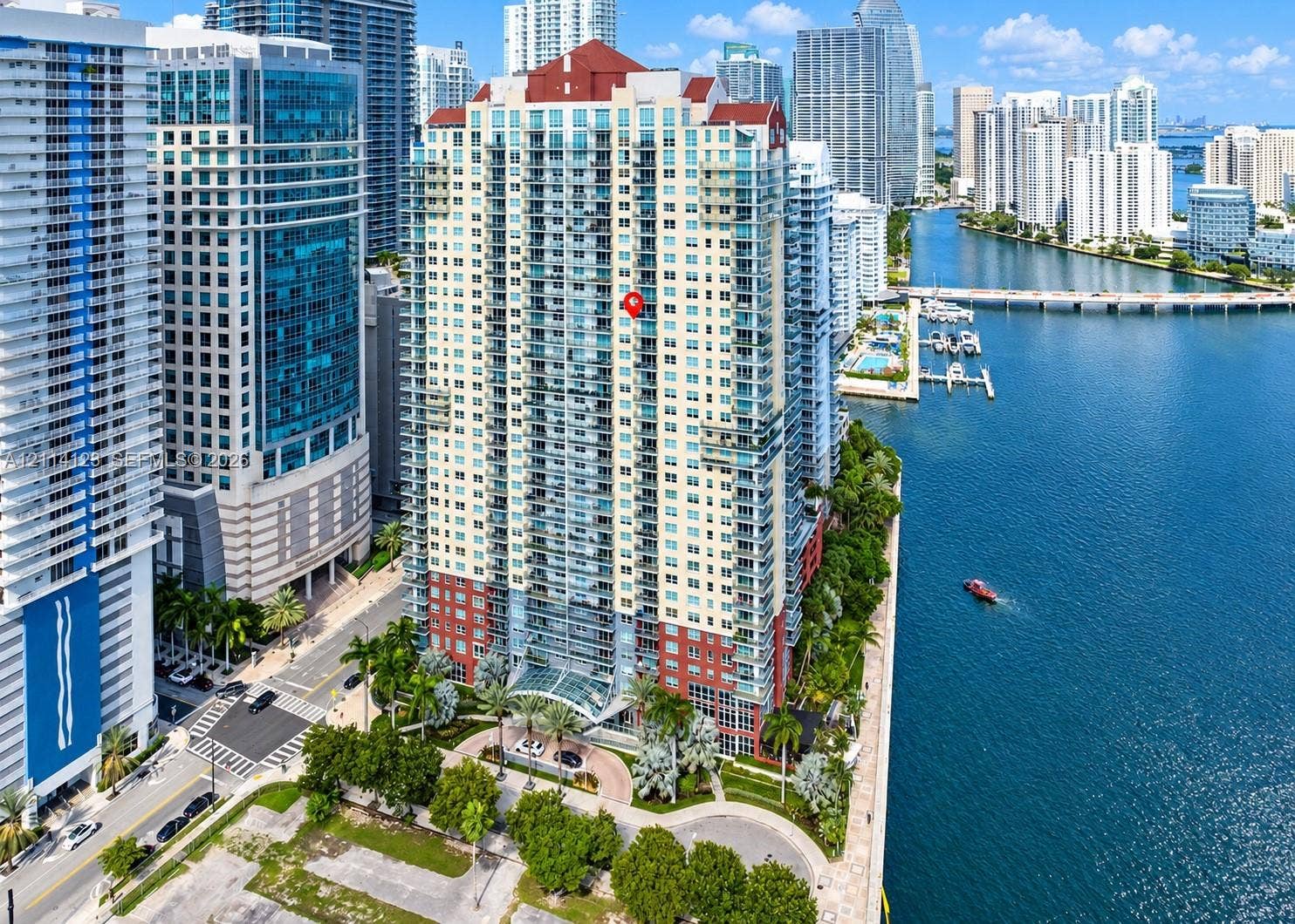 1155 Brickell Bay Drive, #2609, Miami, FL 33131 High-rise residential tower featuring a tiered facade, multi-level balconies, expansive glass windows, and a prominent red pitched roof, situated along the waterfront