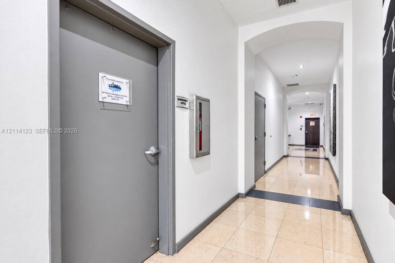 1155 Brickell Bay Drive, #2609, Miami, FL 33131 Interior hallway featuring polished tile flooring, recessed lighting, arched architectural details, and a flush-mounted metal fire extinguisher cabinet