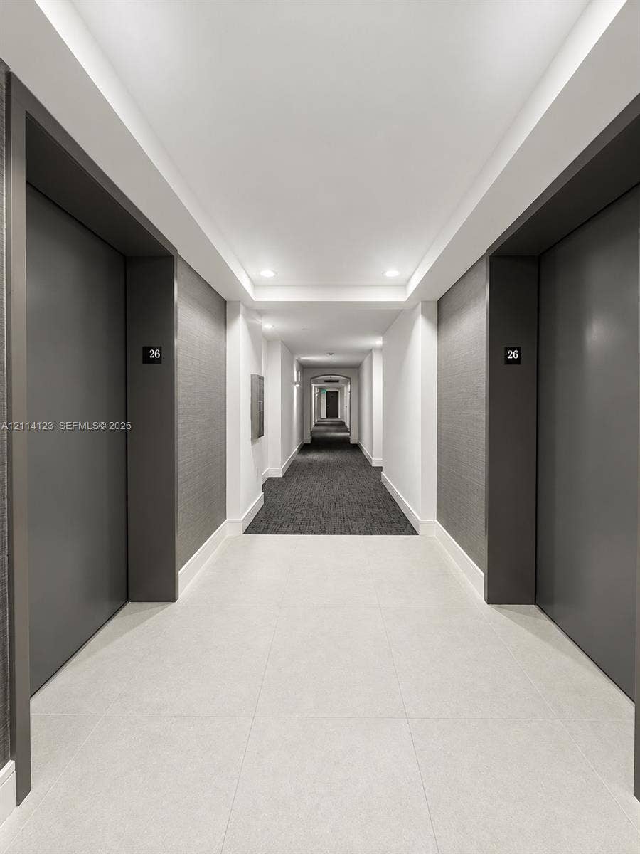 1155 Brickell Bay Drive, #2609, Miami, FL 33131 Hallway featuring large-format tile flooring, textured charcoal wall coverings, matte charcoal door frames, and recessed ceiling lighting