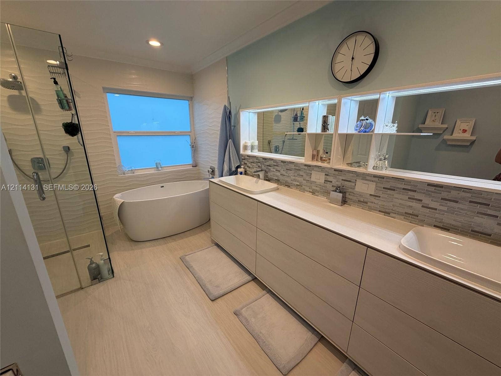 9012 Southern Orchard Road N, Davie, FL 33328 Double vanity with rectangular vessel sinks, freestanding soaking tub, glass-enclosed walk-in shower, horizontal tile backsplash, and light-tone cabinetry
