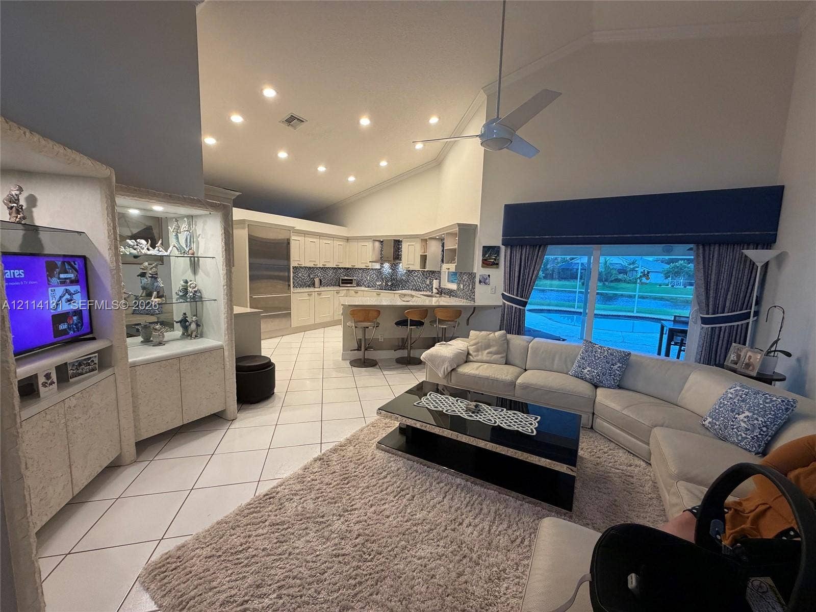 9012 Southern Orchard Road N, Davie, FL 33328 Vaulted ceilings with recessed lighting, tiled flooring, built-in display cabinetry, and a kitchen island with bar seating