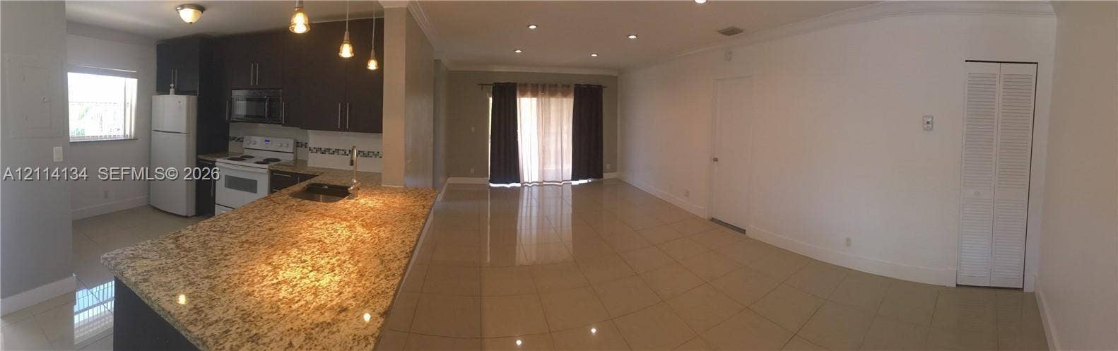12143 Royal Palm Boulevard, #8E, Coral Springs, Coral Springs, FL 33065 Kitchen featuring dark-toned cabinetry, stone-surface countertop with integrated breakfast bar, recessed ceiling lighting, and tile flooring