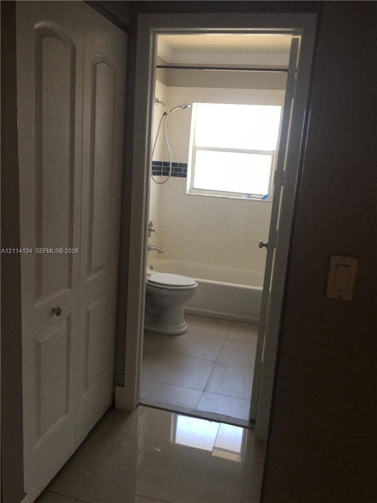 12143 Royal Palm Boulevard, #8E, Coral Springs, Coral Springs, FL 33065 Bathroom featuring a combination bathtub and shower, porcelain tile flooring, and a window for natural light