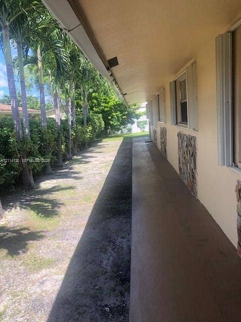 2323 Scott Street, #Front, Hollywood, Hollywood, FL 33020 Covered concrete exterior walkway featuring vertical stone masonry accents and aluminum window shutters