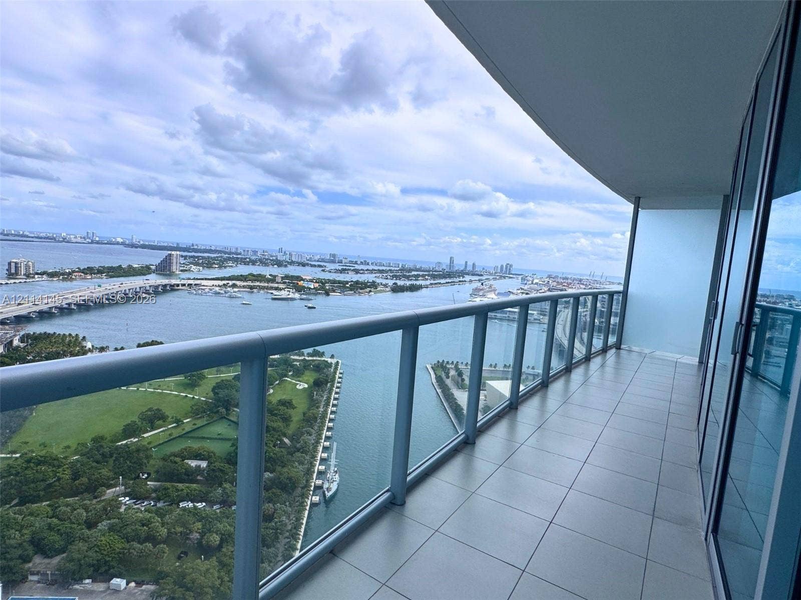 Covered balcony featuring large-format tile flooring and a glass-paneled railing