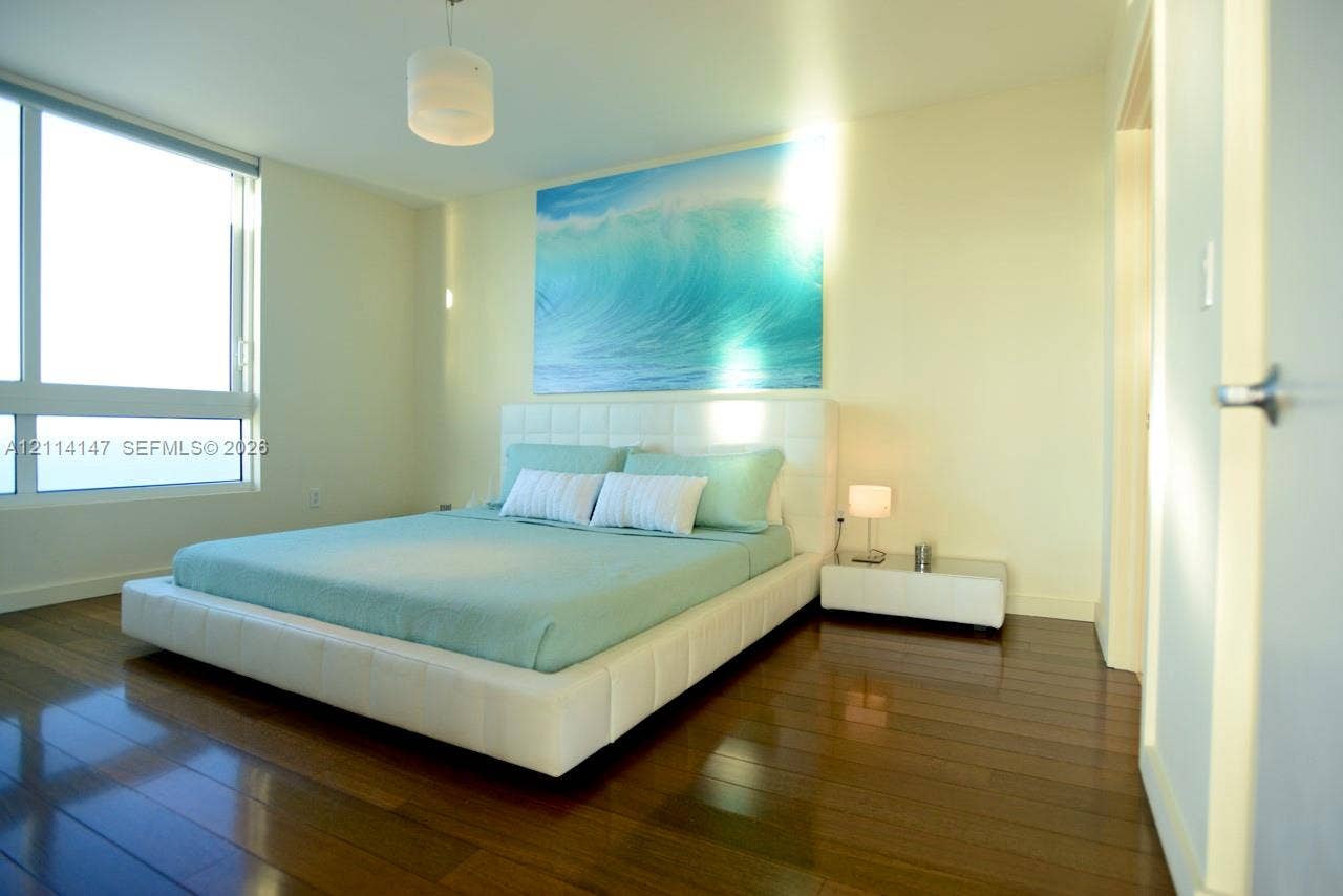 6365 Collins Avenue, #3908, Miami Beach, FL 33141 Floor-to-ceiling windows, wood-finish flooring, and a minimalist pendant light fixture