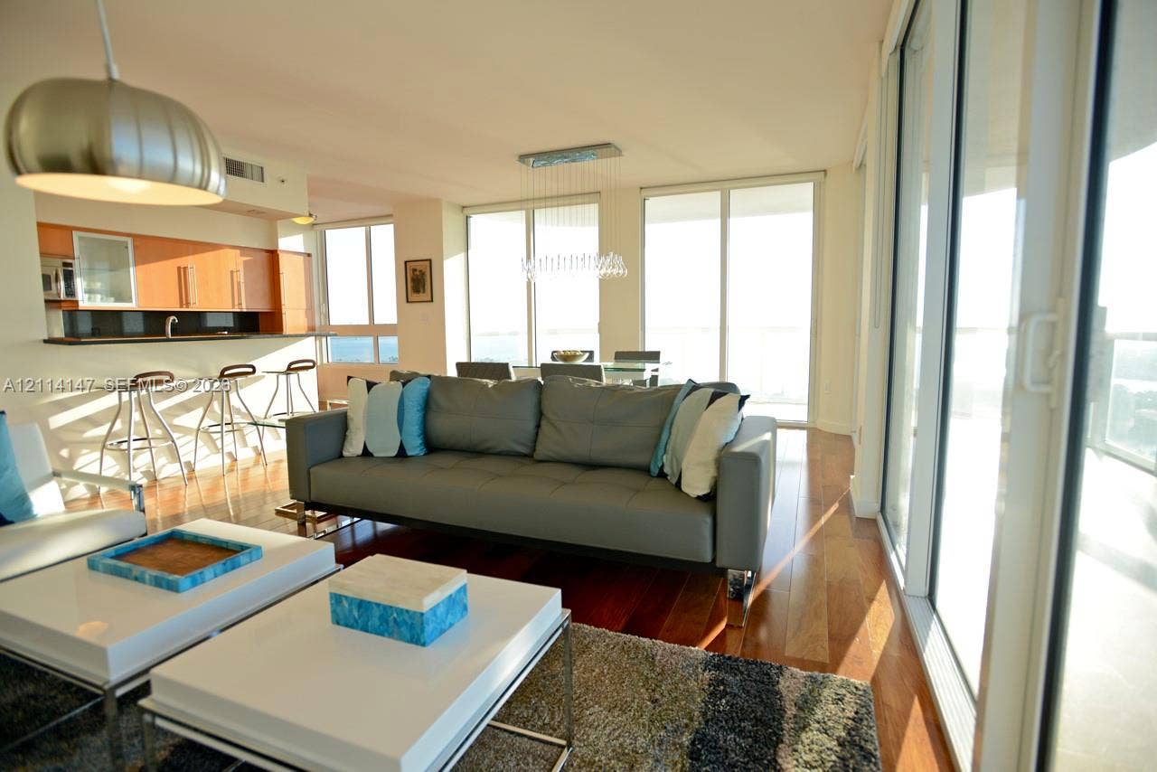 6365 Collins Avenue, #3908, Miami Beach, FL 33141 Open-concept floor plan featuring wood-finish flooring, floor-to-ceiling glass sliding doors, built-in cabinetry, and integrated pendant lighting