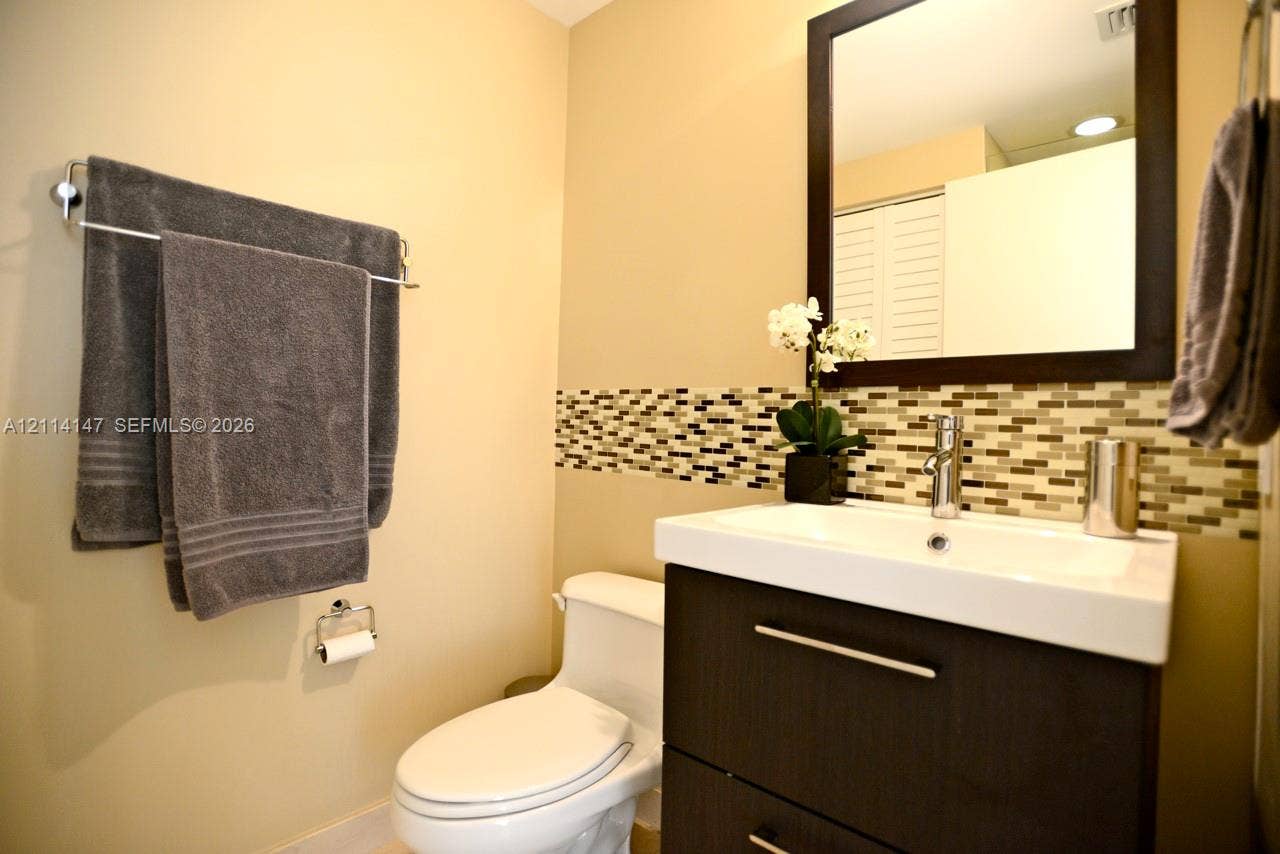 6365 Collins Avenue, #3908, Miami Beach, FL 33141 Modern vanity with a rectangular sink, espresso-finish cabinetry, mosaic tile backsplash, and a framed mirror