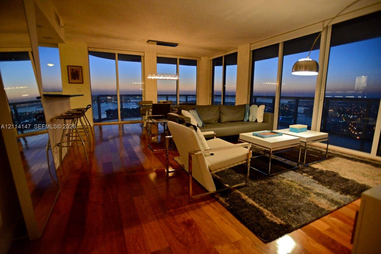 6365 Collins Avenue, #3908, Miami Beach, FL 33141 Open-concept living space featuring wood-finish flooring, floor-to-ceiling glass windows, and a built-in breakfast bar