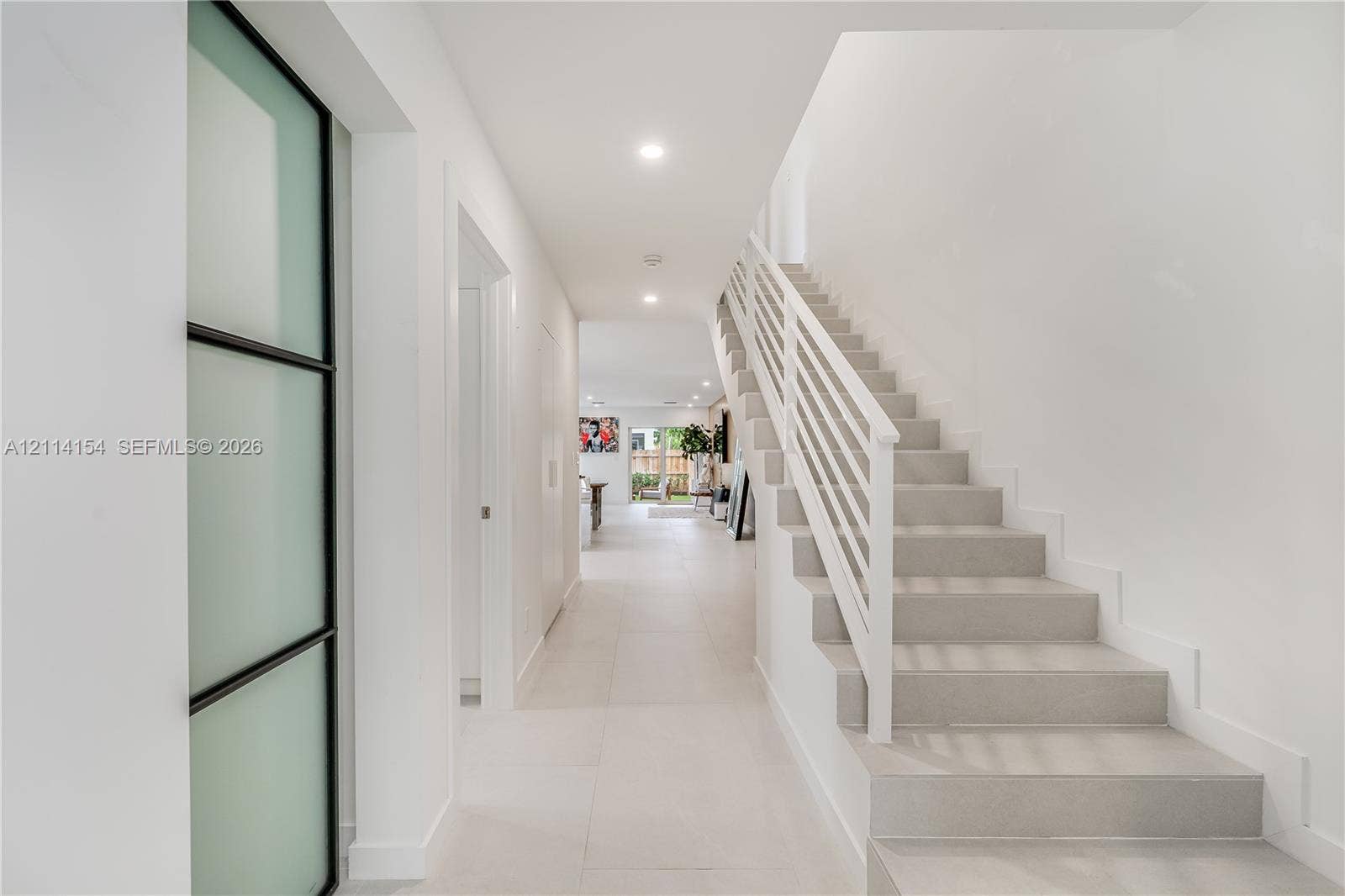 1126 NE 2nd Avenue, Fort Lauderdale, FL 33304 Entryway featuring large-format tile flooring, a staircase with white horizontal railings, recessed lighting, and a frosted glass door with a black frame