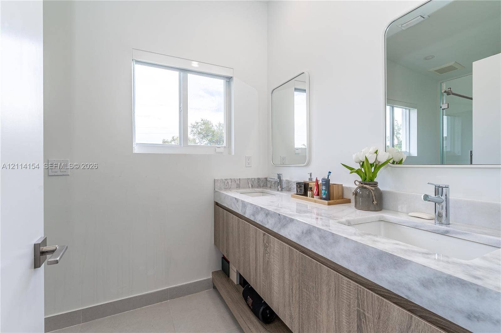 1126 NE 2nd Avenue, Fort Lauderdale, FL 33304 Dual-sink floating vanity with wood-finish cabinetry, stone-style countertop, rectangular undermount sinks, and rounded rectangular mirrors