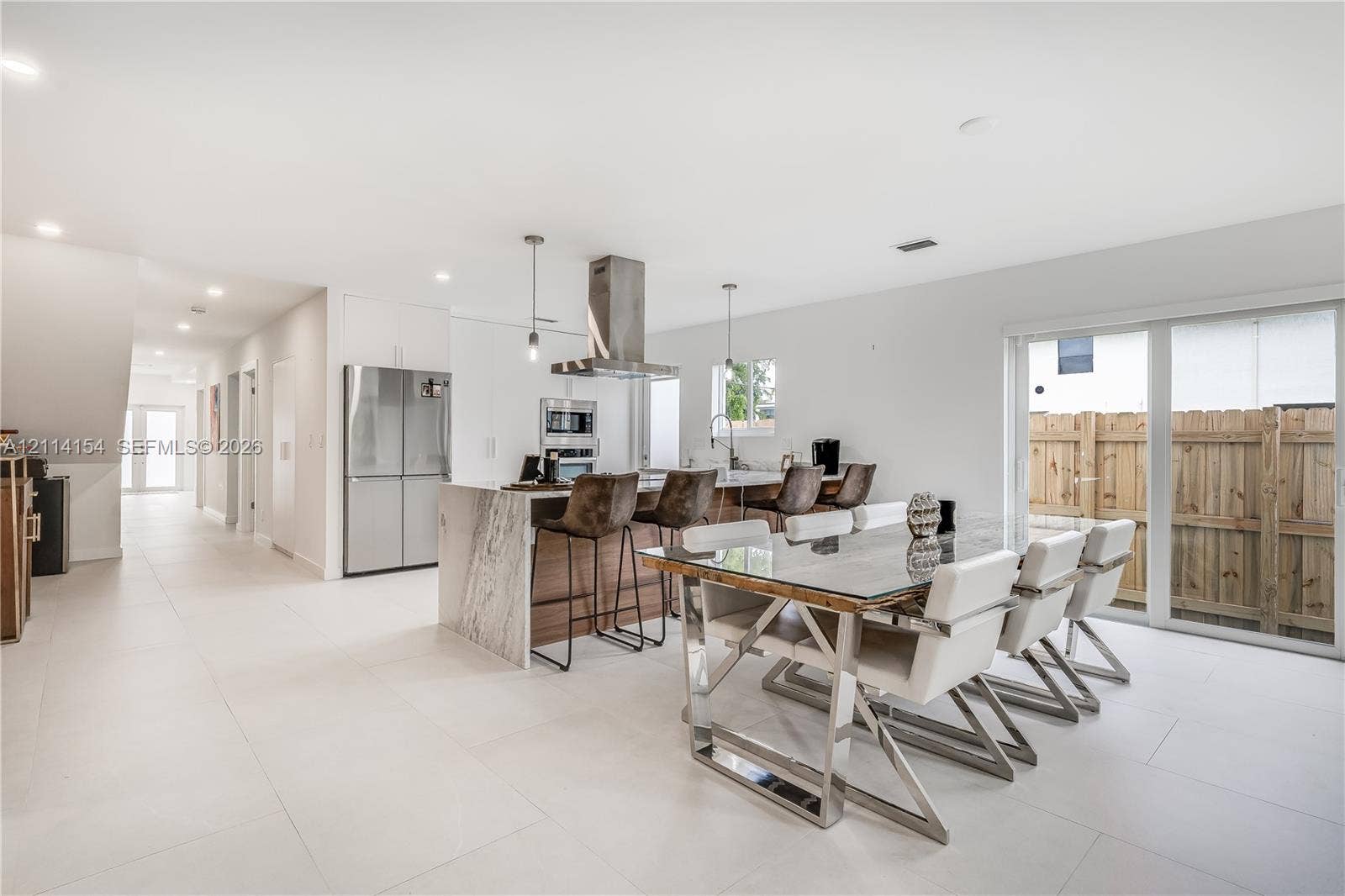 1126 NE 2nd Avenue, Fort Lauderdale, FL 33304 Kitchen featuring a waterfall-edge island, stone-patterned countertop, stainless steel appliances, stainless steel range hood, and large-format tile flooring