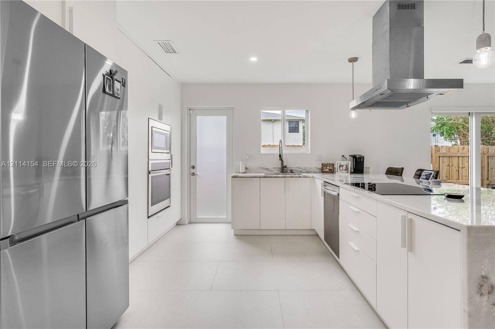 1126 NE 2nd Avenue, Fort Lauderdale, FL 33304 Modern kitchen featuring flat-panel cabinetry, stone countertops, stainless steel appliances, a chimney-style range hood, and large-format tile flooring