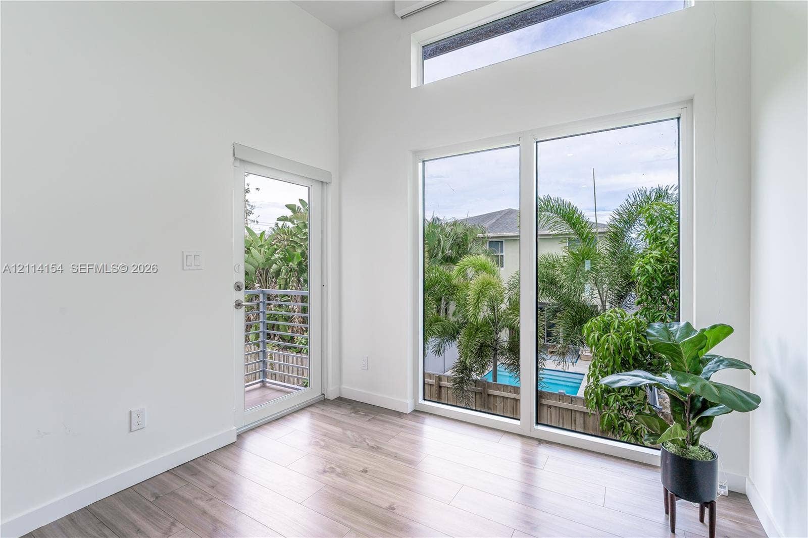 1126 NE 2nd Avenue, Fort Lauderdale, FL 33304 High ceilings featuring expansive picture windows and clerestory glass, wood-finish flooring, and a glass-panel exterior door opening to a balcony