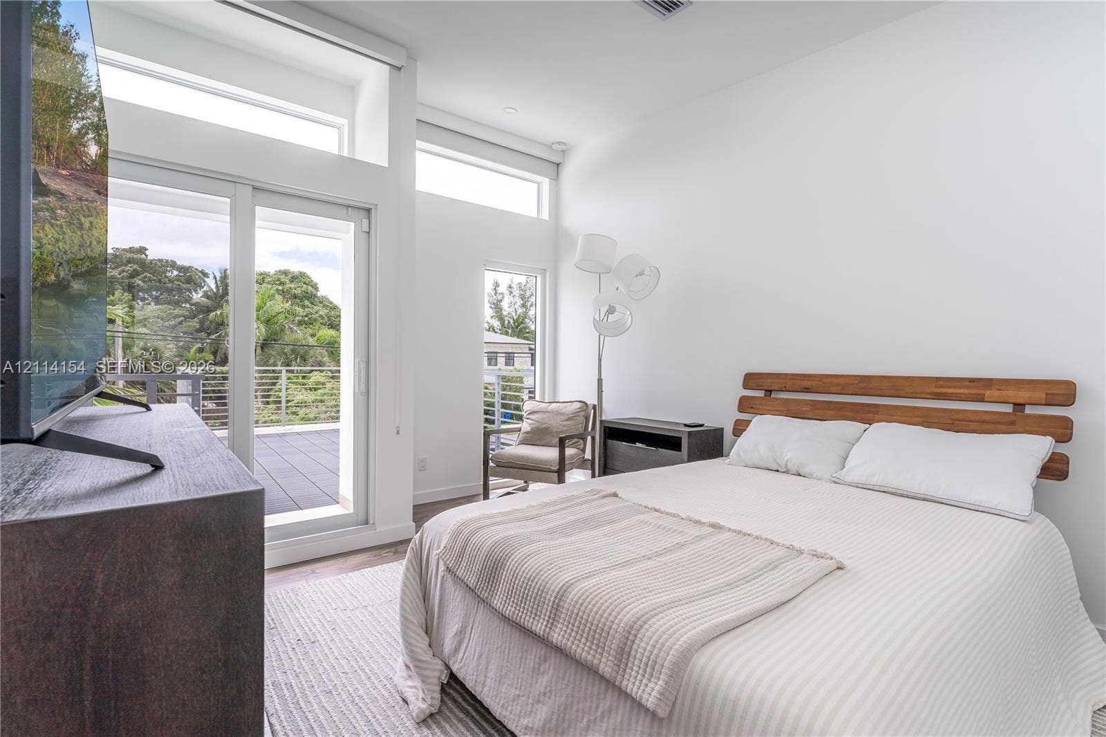 1126 NE 2nd Avenue, Fort Lauderdale, FL 33304 High-ceilinged room featuring expansive clerestory windows, a full-height glass door, and a private balcony with horizontal metal railings