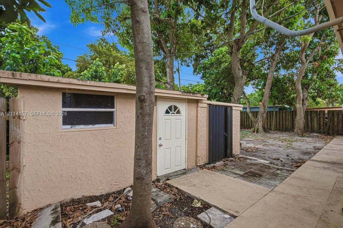 2580 NW 62nd Avenue, Margate, FL 33063 Exterior storage structure featuring a stucco finish, single-entry door with glass detail, horizontal sliding window, and metal privacy screen