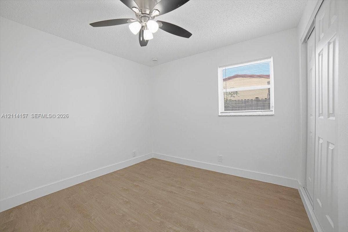 2580 NW 62nd Avenue, Margate, FL 33063 Neutral-toned wood-finish flooring, ceiling fan with integrated lighting, window with blinds, and dual-panel sliding closet doors