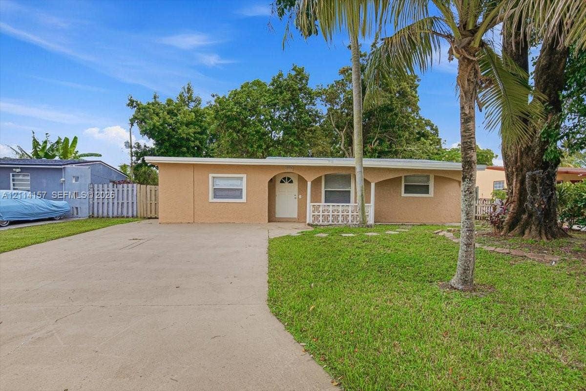 2580 NW 62nd Avenue, Margate, FL 33063 Single-story residence featuring a stucco exterior, concrete driveway, arched covered porch entry, decorative privacy screen, and mature landscaping