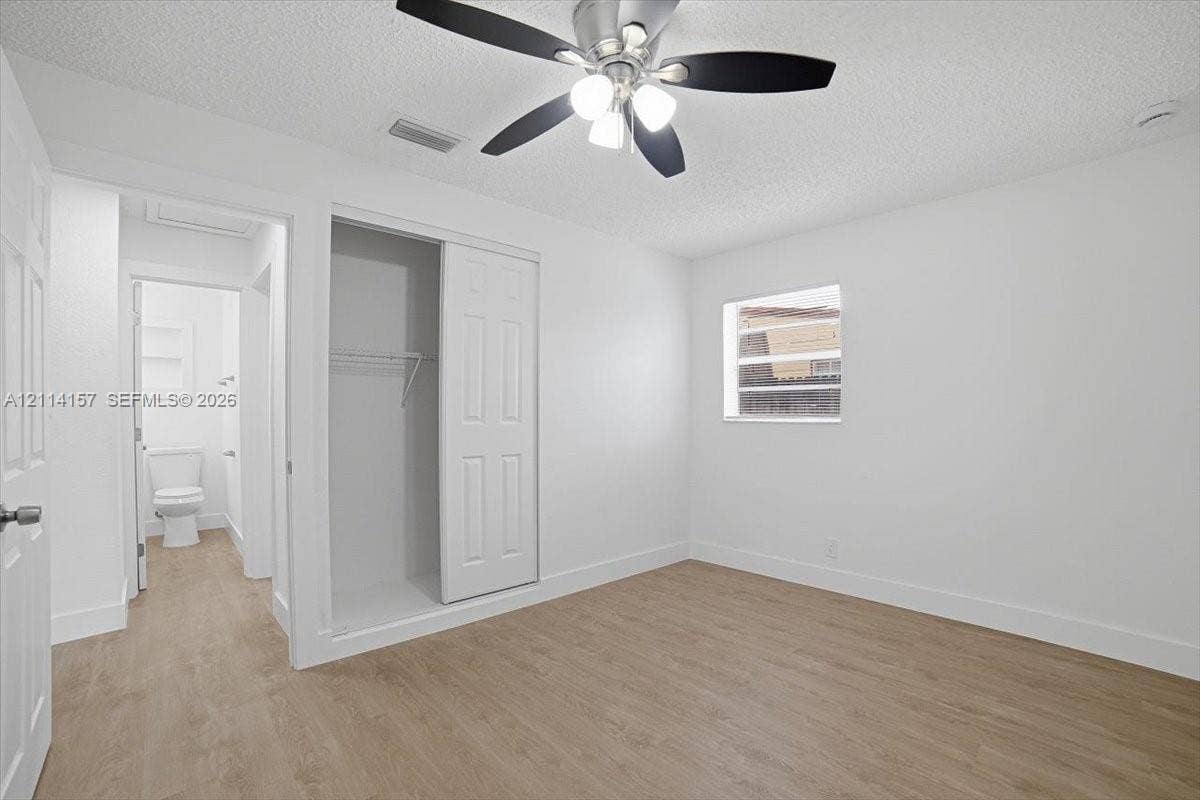 2580 NW 62nd Avenue, Margate, FL 33063 Room featuring wood-finish flooring, a ceiling fan with integrated lighting, a sliding-door closet, and white wall finishes