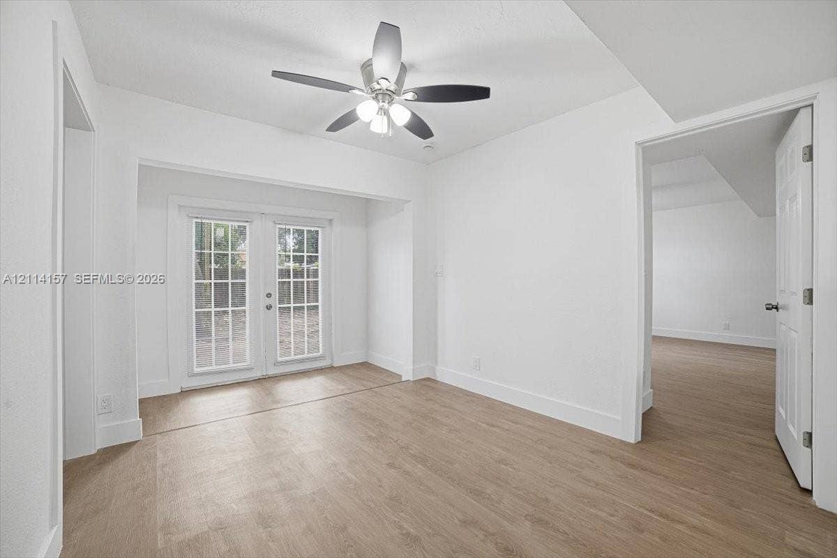 2580 NW 62nd Avenue, Margate, FL 33063 Wood-finish flooring, white paneled interior doors, and glass-paned French doors with a multi-light design, complemented by a central ceiling fan with integrated lighting