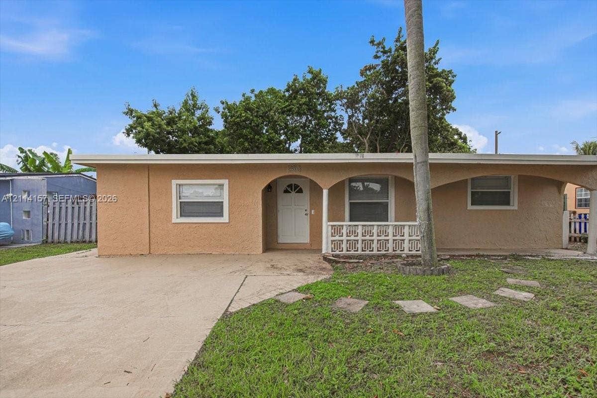 2580 NW 62nd Avenue, Margate, FL 33063 Single-story exterior featuring a stucco facade, covered front porch with arched openings, decorative concrete block screening, and a concrete driveway