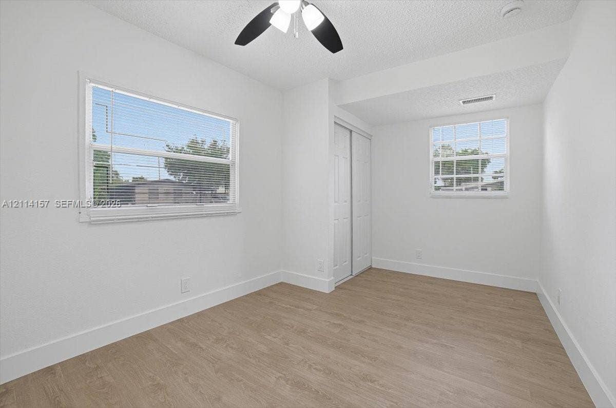 2580 NW 62nd Avenue, Margate, FL 33063 Interior room featuring wood-finish flooring, dual windows with integrated blinds, and a built-in closet with sliding panel doors