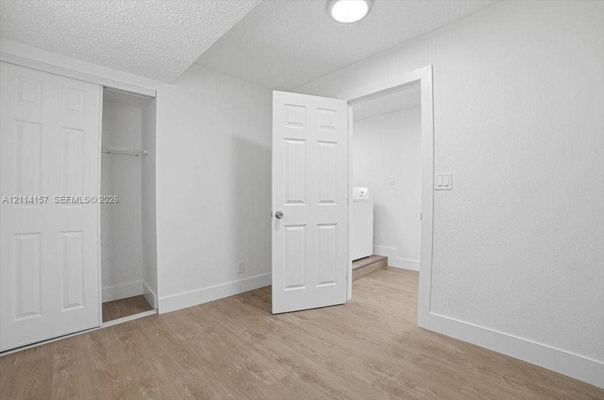 2580 NW 62nd Avenue, Margate, FL 33063 Interior space featuring wood-finish flooring, white six-panel doors, and built-in closet storage with a metal hanging rod