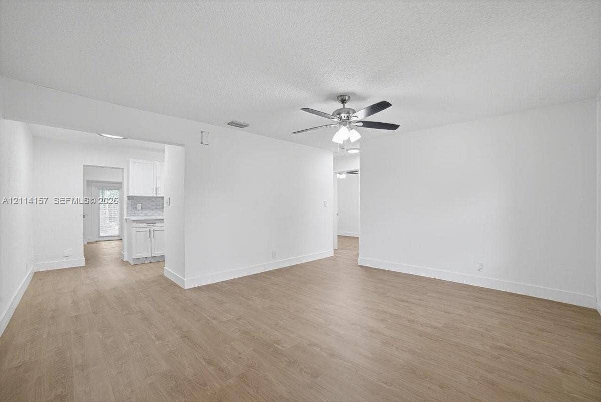 2580 NW 62nd Avenue, Margate, FL 33063 Interior space featuring wood-finish flooring, white walls, and a ceiling-mounted light fixture with a multi-blade fan
