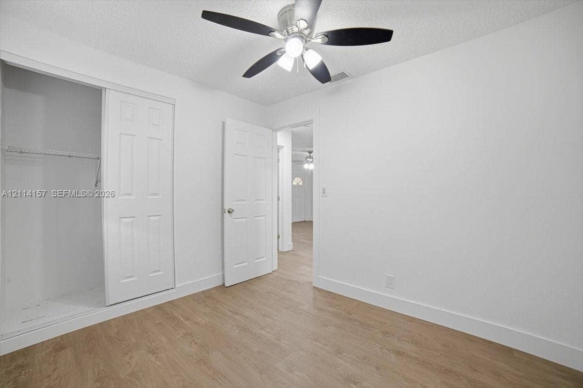 2580 NW 62nd Avenue, Margate, FL 33063 Room featuring wood-finish flooring, a ceiling fan with integrated lighting, and a closet with sliding paneled doors