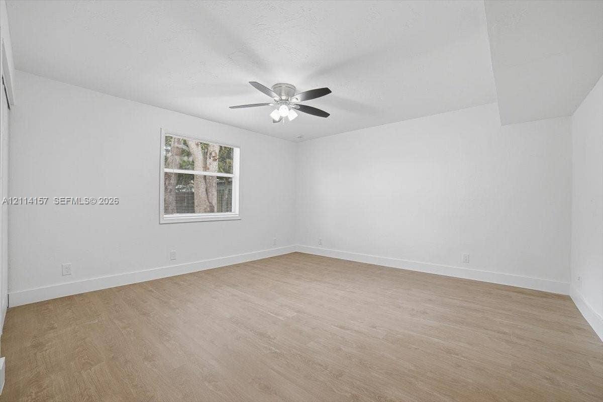 2580 NW 62nd Avenue, Margate, FL 33063 Bright room featuring wood-finish flooring, a neutral color palette, a single-hung window, and a multi-blade ceiling fan with integrated lighting