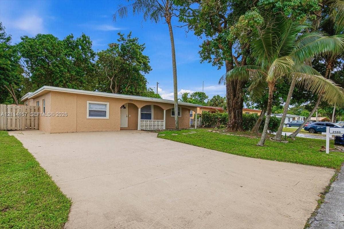 2580 NW 62nd Avenue, Margate, FL 33063 Stucco exterior featuring a covered front porch with arched detailing, concrete driveway, and mature landscaping