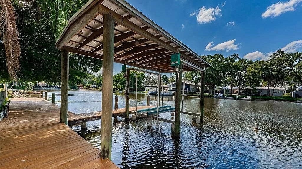 Waterfront wooden dock featuring a covered boat slip with a mechanical lift