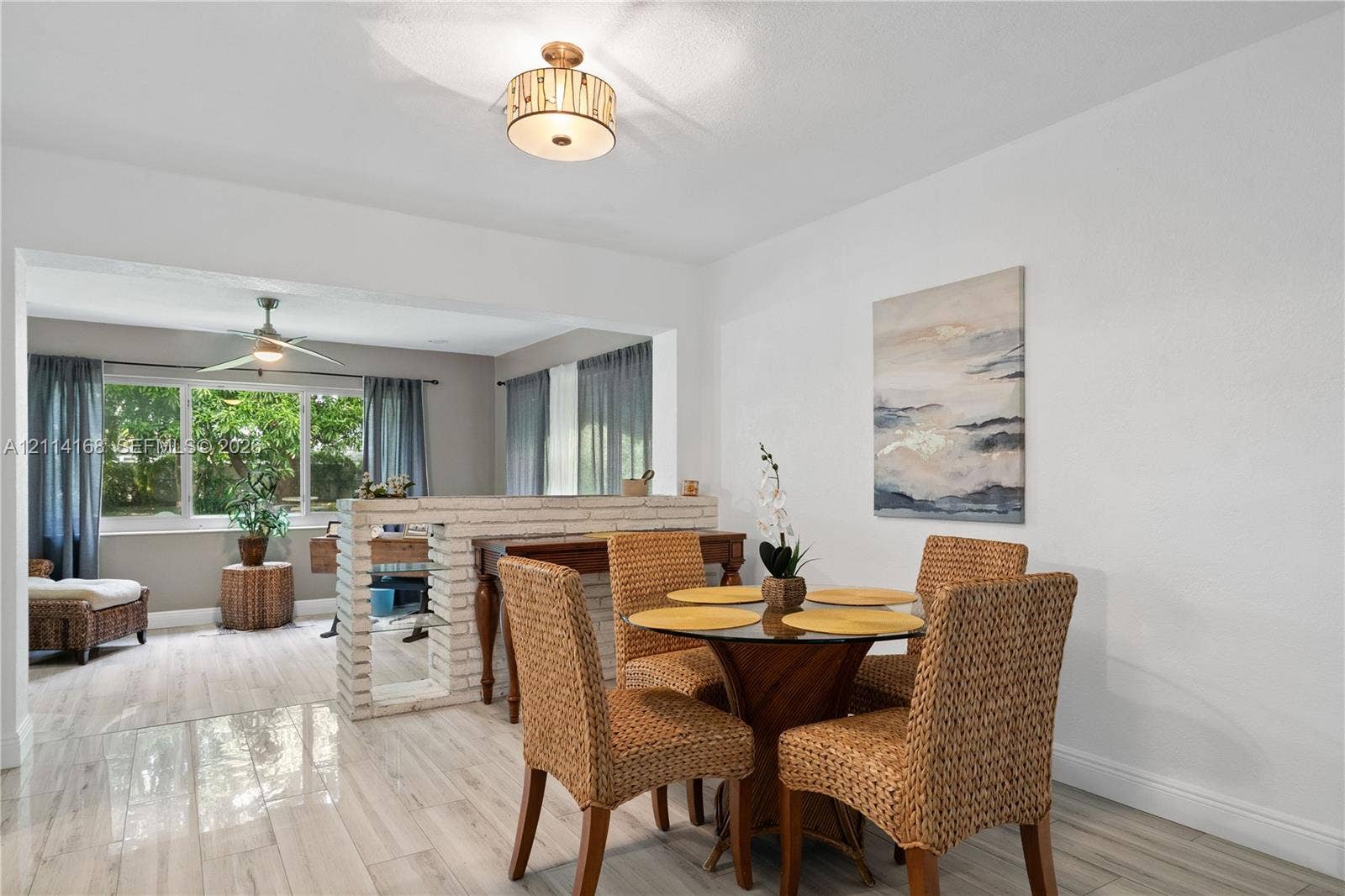 Italian Tile flooring throughout, low-profile brick partition wall, drum-style ceiling light fixture, ceiling fan, and large windows