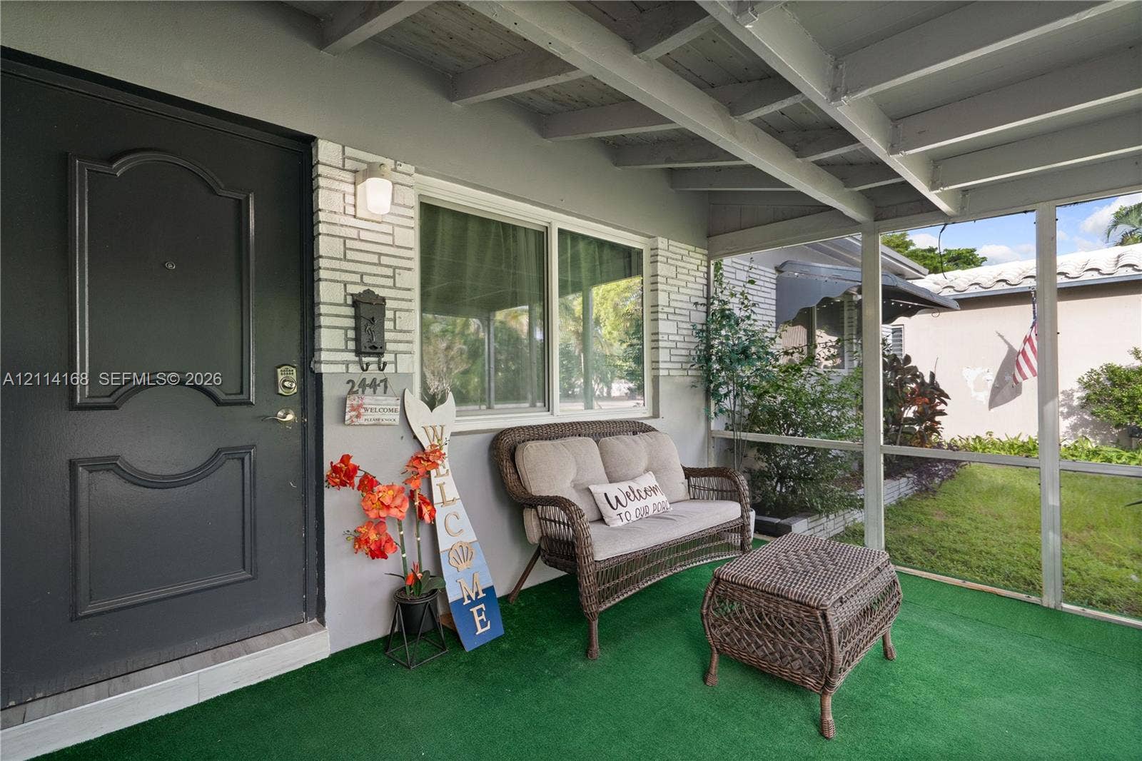 Screened-in porch featuring a painted brick facade, an exterior door with architectural paneling, and an exposed beam ceiling