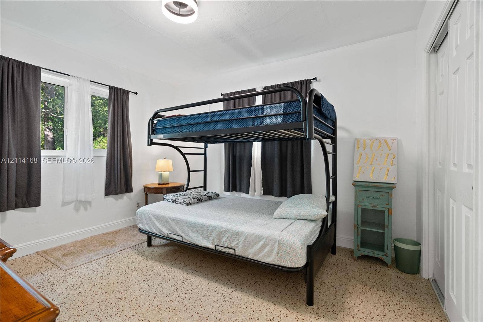 2nd Bedroopm Neutral interior room featuring terrazzo flooring, dual-aspect windows, and a closet with sliding panel doors