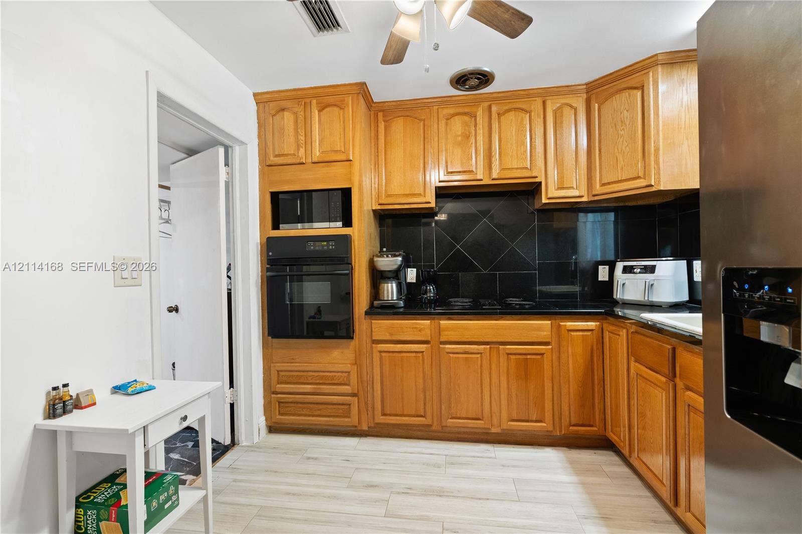 Kitchen featuring wood cabinetry, integrated wall oven, dark tile backsplash