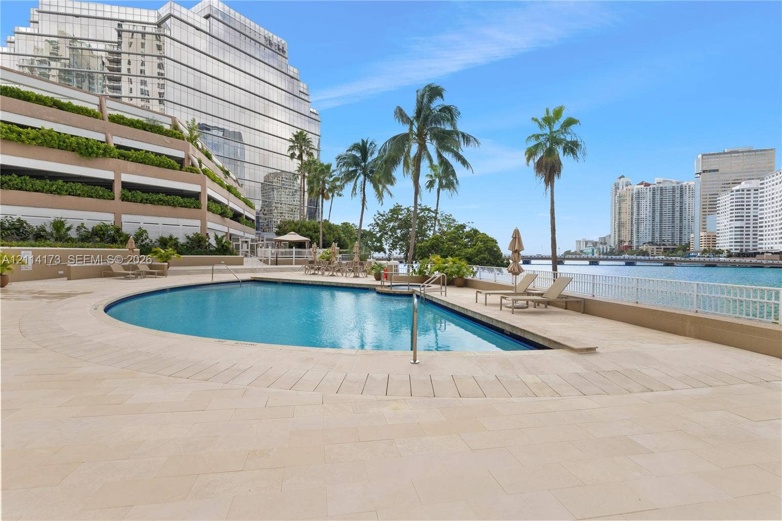 701 Brickell Key Boulevard, #1012, Miami, FL 33131 Waterfront swimming pool with stone-tiled deck, integrated spa, and mature palm landscaping