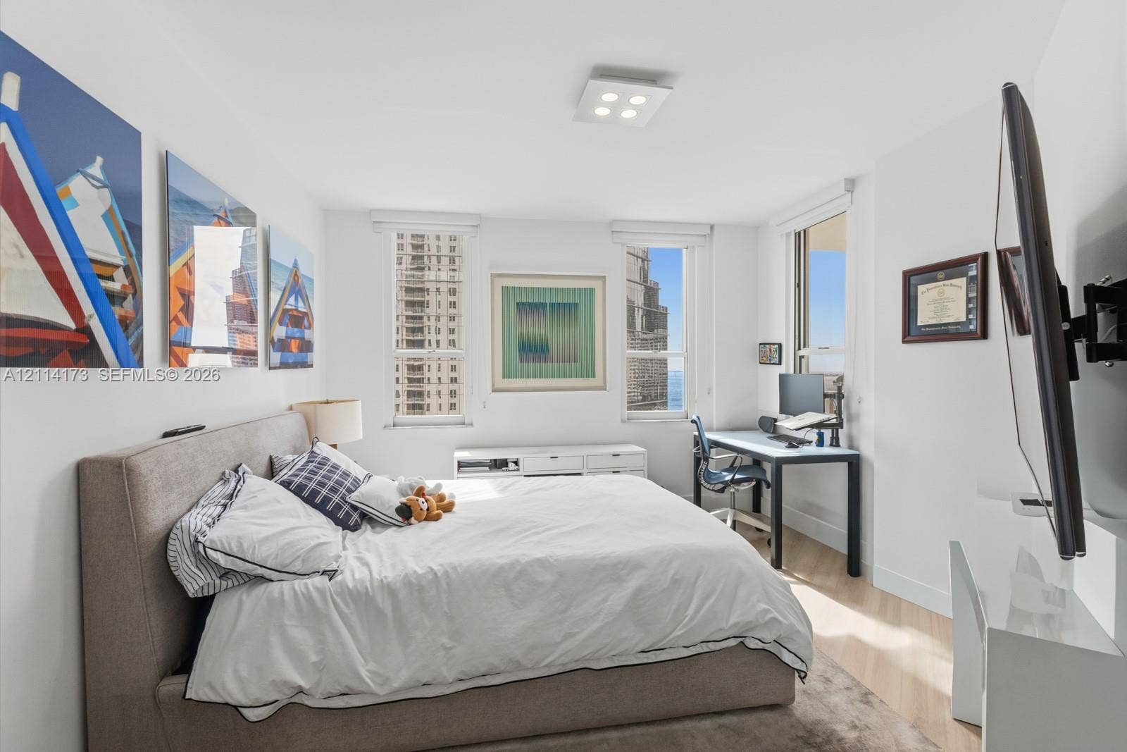 701 Brickell Key Boulevard, #1012, Miami, FL 33131 Bright room featuring wood-finish flooring, white walls, triple window configuration, and a square modern flush-mount ceiling light fixture