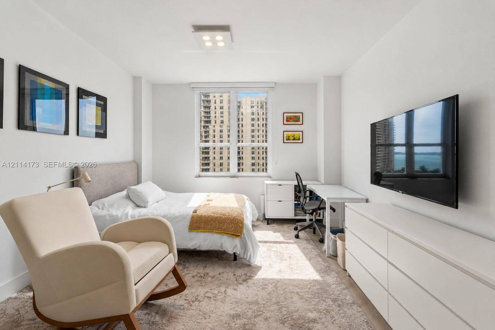 701 Brickell Key Boulevard, #1012, Miami, FL 33131 Bright interior space featuring a large window with urban and water scenery, neutral wall finishes, and a modern ceiling-mounted light fixture