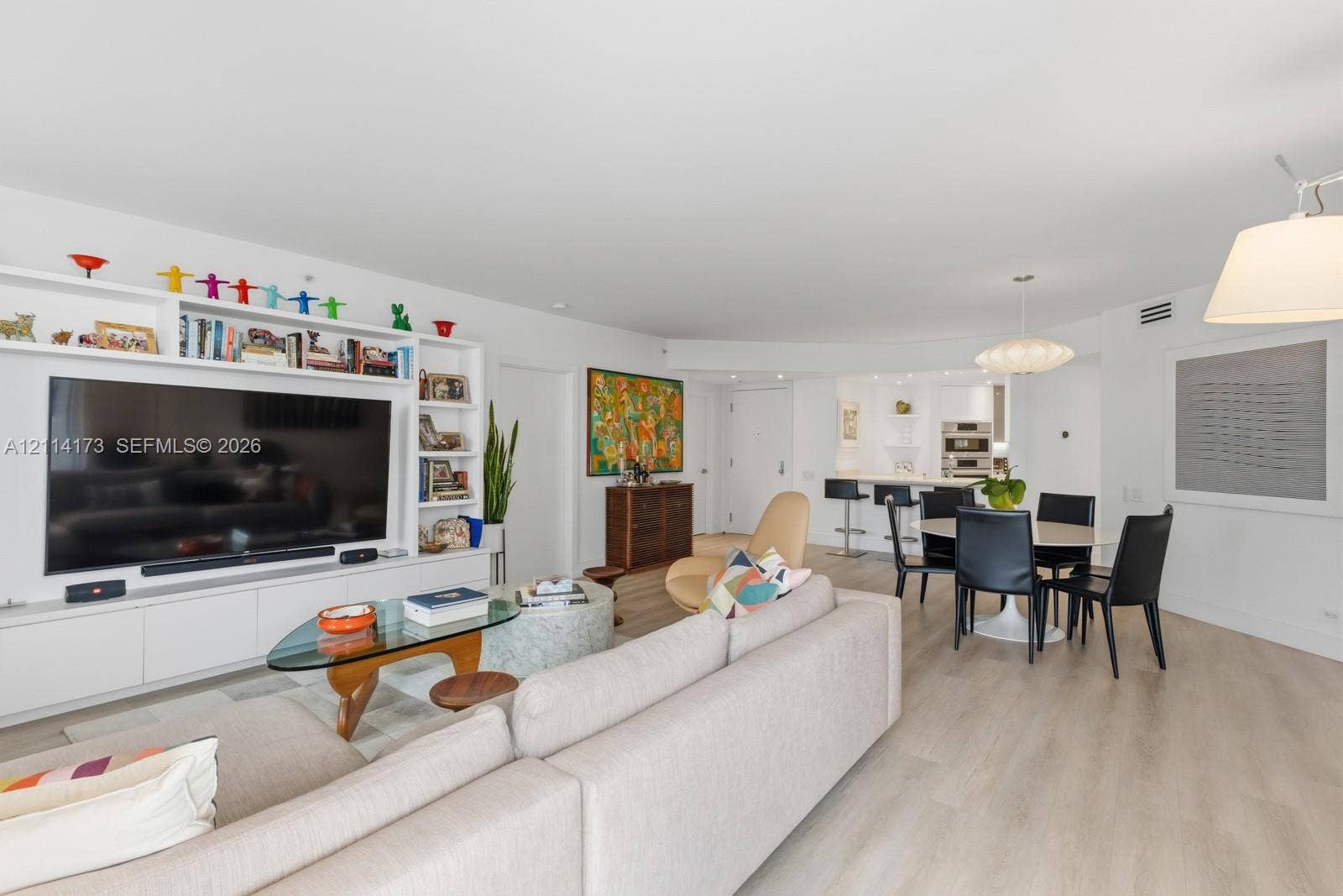 701 Brickell Key Boulevard, #1012, Miami, FL 33131 Open-concept floor plan featuring light wood-finish flooring, custom built-in cabinetry with integrated shelving, recessed lighting, and a kitchen island with stone countertop