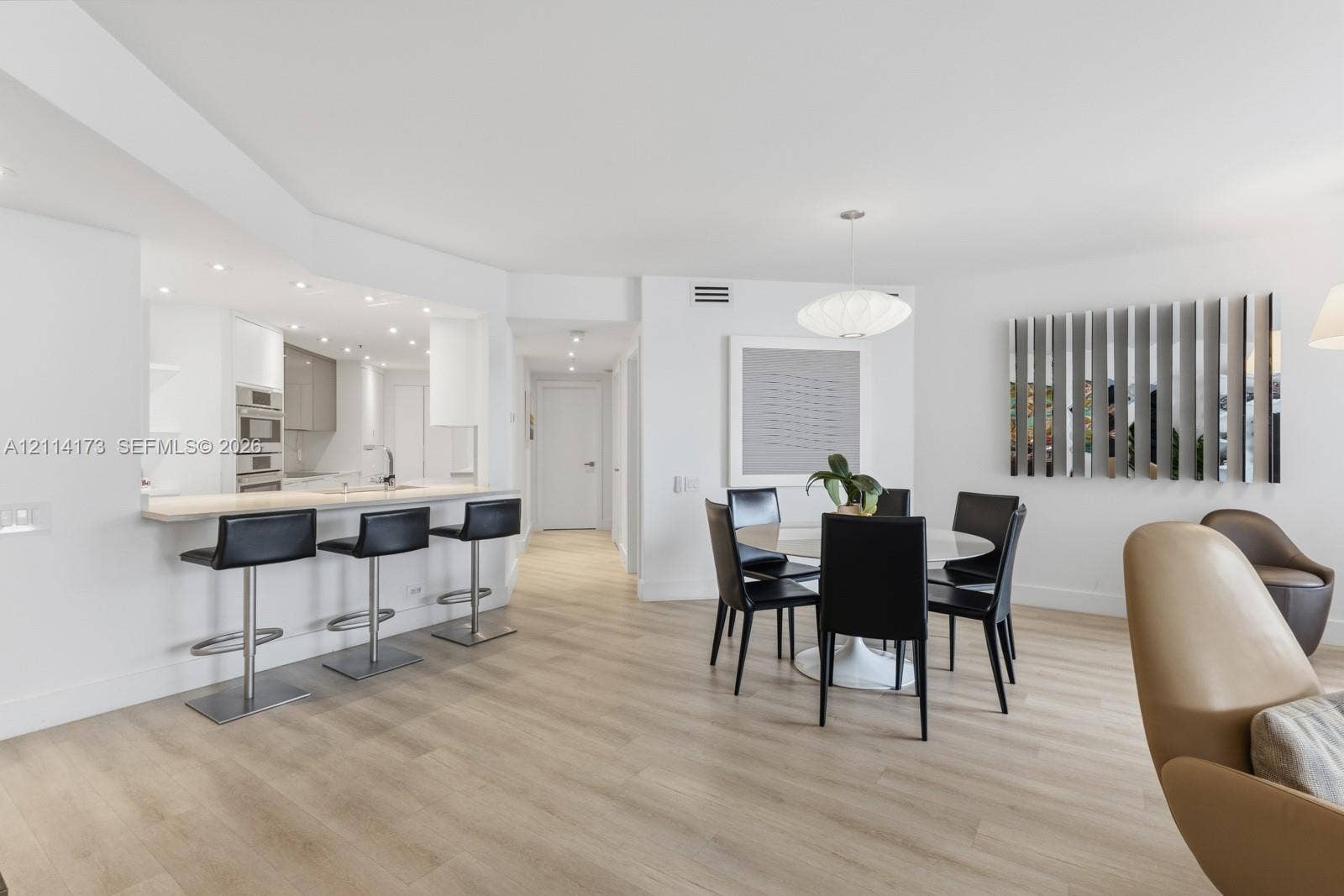 701 Brickell Key Boulevard, #1012, Miami, FL 33131 Open-concept space featuring light wood-finish flooring, recessed lighting, built-in kitchen cabinetry with integrated stainless steel appliances, and a quartz-topped breakfast bar