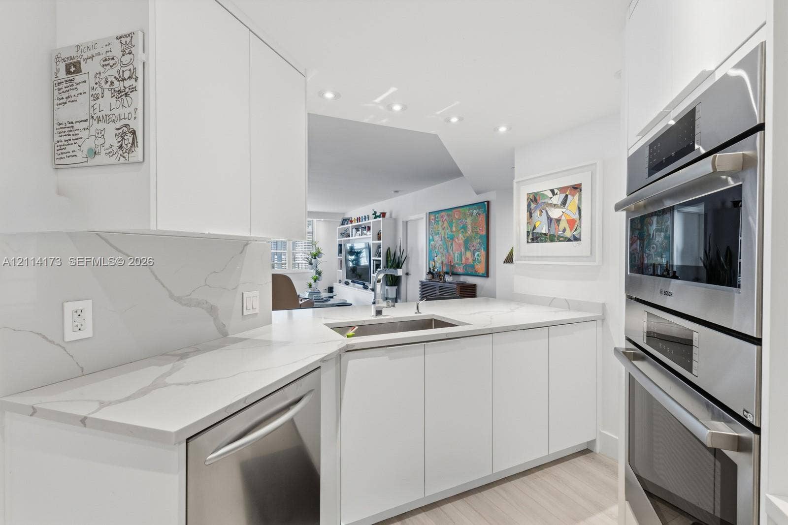 701 Brickell Key Boulevard, #1012, Miami, FL 33131 Kitchen featuring white cabinetry, veined solid-surface countertops, stainless steel undermount sink, and integrated stainless steel double wall ovens